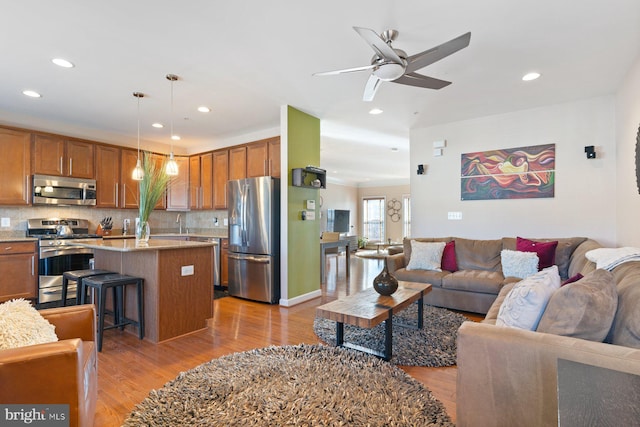 living room featuring ceiling fan, sink, and light hardwood / wood-style floors