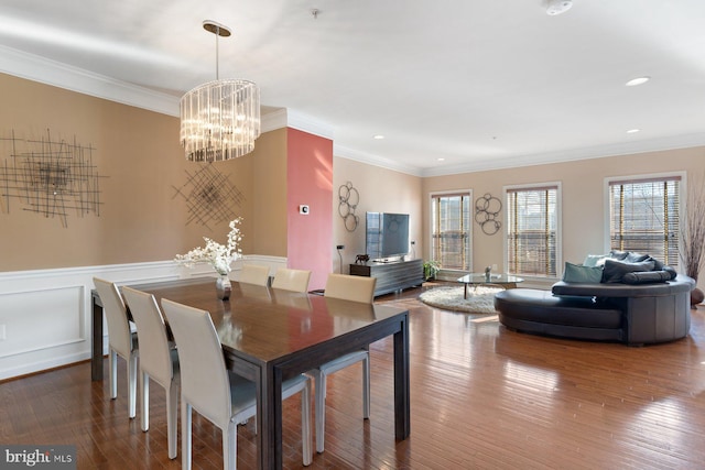 dining area with hardwood / wood-style flooring, ornamental molding, and a chandelier