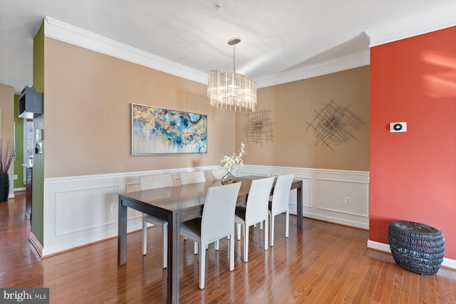 dining area with an inviting chandelier, hardwood / wood-style floors, and crown molding