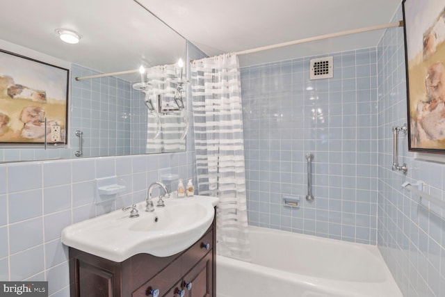 bathroom featuring vanity, tile walls, and shower / bath combo with shower curtain