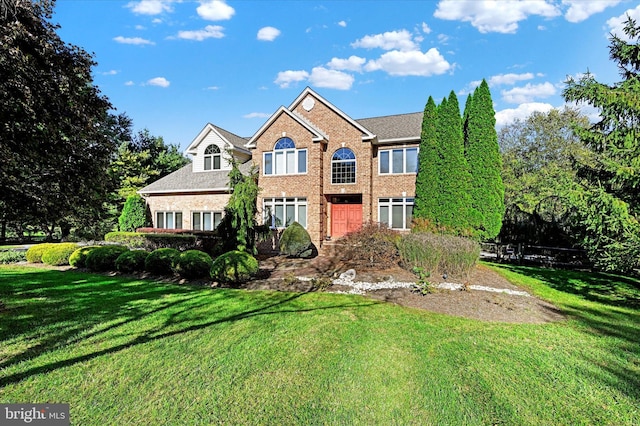 view of front facade with brick siding and a front yard