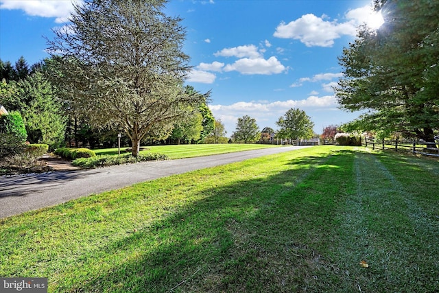 exterior space featuring a lawn, driveway, and fence