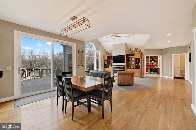 dining area with light wood finished floors, baseboards, a ceiling fan, and lofted ceiling