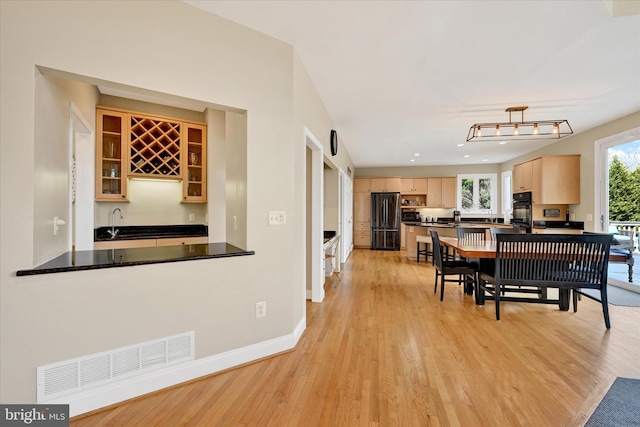 unfurnished dining area with visible vents, baseboards, light wood-style flooring, and indoor wet bar