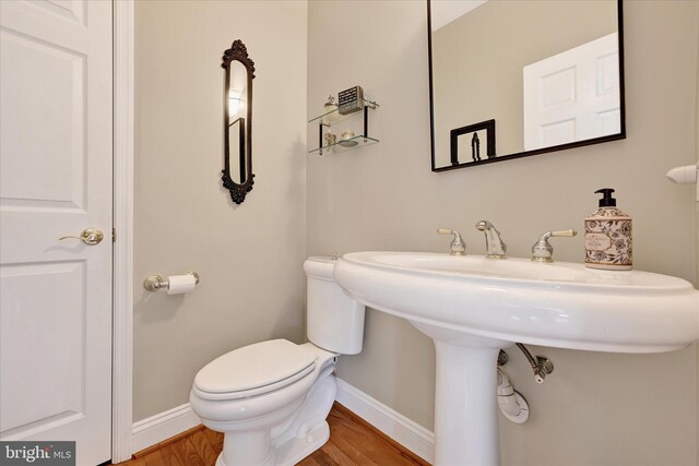 half bath featuring toilet, baseboards, and wood finished floors