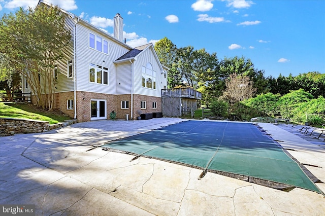 view of swimming pool featuring a covered pool, a patio, and a deck