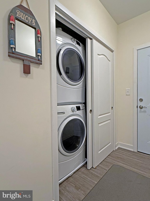 washroom with stacked washer and clothes dryer and light hardwood / wood-style floors