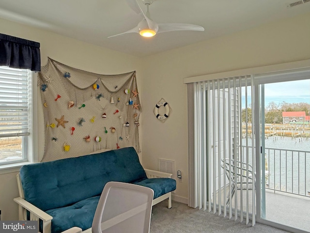 sitting room with carpet, ceiling fan, and a water view