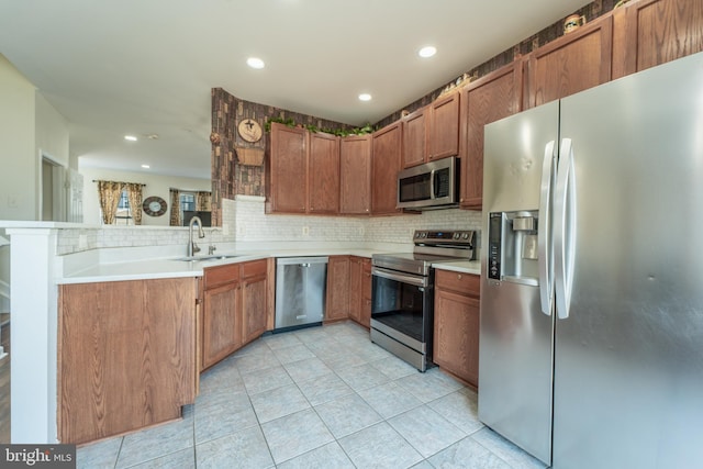 kitchen featuring sink, decorative backsplash, kitchen peninsula, and appliances with stainless steel finishes