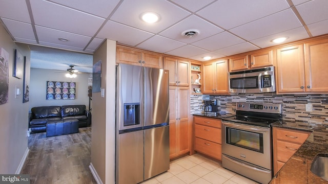 kitchen with tasteful backsplash, a paneled ceiling, stainless steel appliances, and dark stone countertops