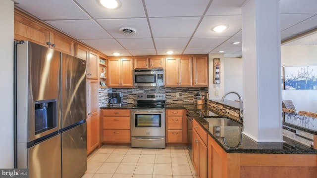 kitchen featuring sink, tasteful backsplash, dark stone countertops, appliances with stainless steel finishes, and kitchen peninsula