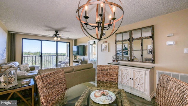 living room with ceiling fan with notable chandelier and a textured ceiling