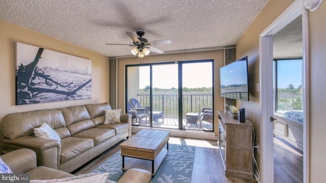 living room with hardwood / wood-style flooring, ceiling fan, a textured ceiling, and a wealth of natural light