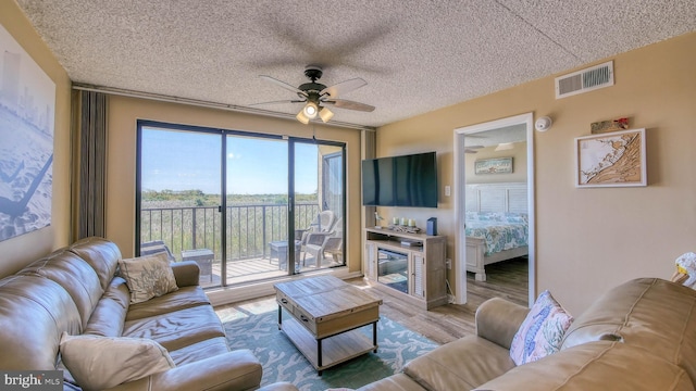 living room featuring hardwood / wood-style floors, a textured ceiling, and ceiling fan