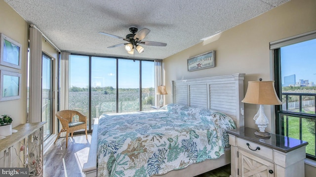 bedroom with ceiling fan, floor to ceiling windows, light hardwood / wood-style floors, and a textured ceiling