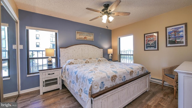 bedroom with multiple windows, dark hardwood / wood-style flooring, and a textured ceiling