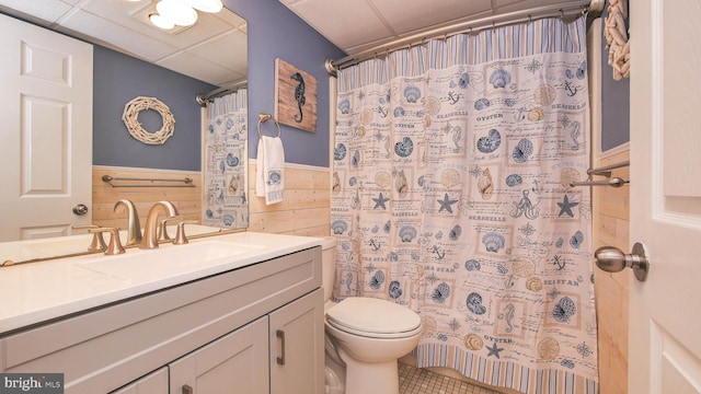 bathroom with toilet, a paneled ceiling, vanity, wooden walls, and a shower with shower curtain