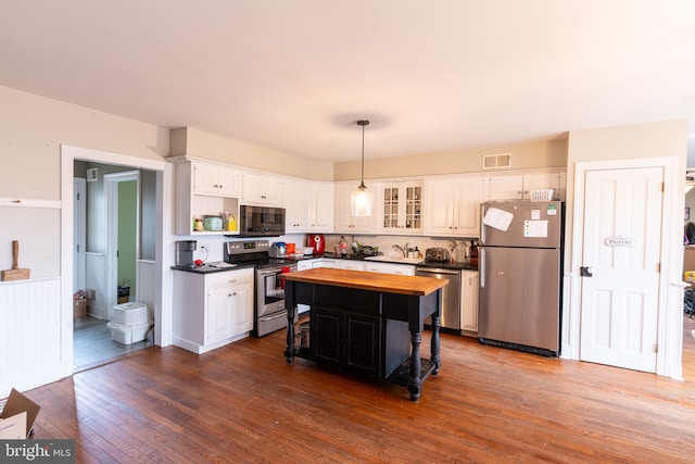 kitchen featuring appliances with stainless steel finishes, dark hardwood / wood-style floors, white cabinetry, butcher block counters, and a center island