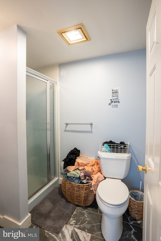 bathroom featuring a shower with door and toilet