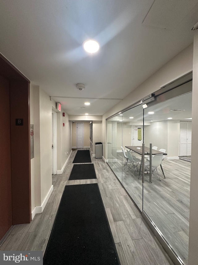 hallway with elevator and wood-type flooring