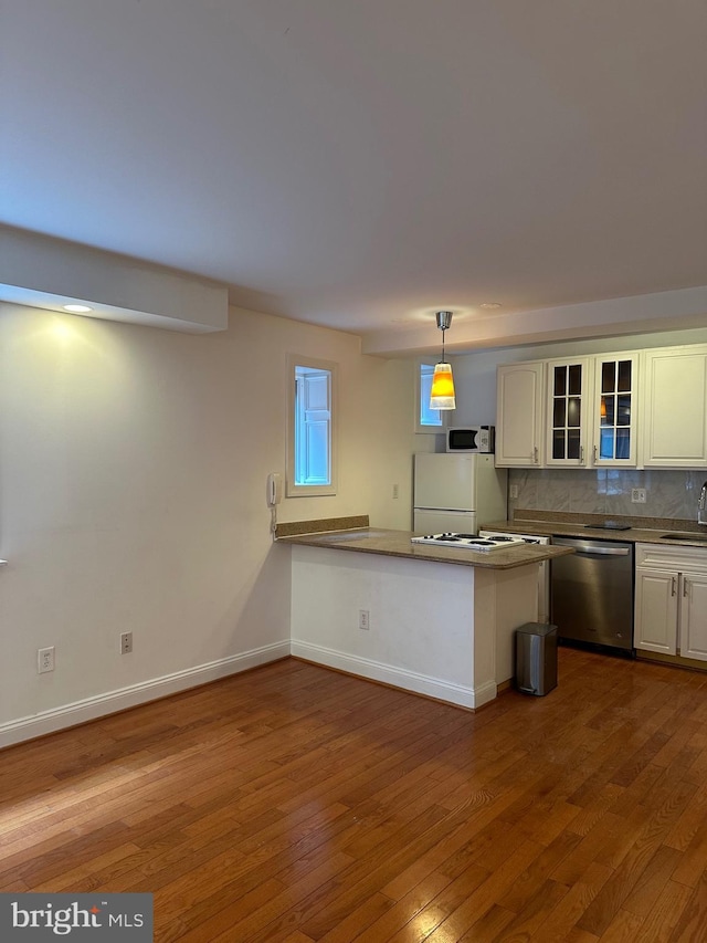 kitchen featuring white appliances, kitchen peninsula, sink, and hardwood / wood-style floors