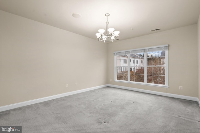 empty room featuring carpet flooring and a chandelier