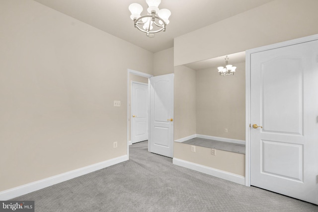 empty room featuring light carpet and a notable chandelier