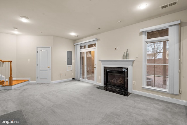 unfurnished living room featuring a premium fireplace, electric panel, and light carpet