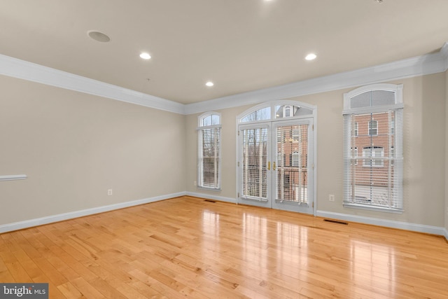 spare room featuring ornamental molding and light hardwood / wood-style flooring