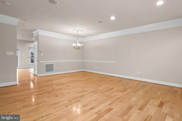 spare room with crown molding, an inviting chandelier, and light hardwood / wood-style flooring