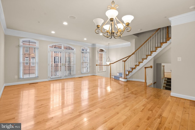 unfurnished living room with crown molding, a chandelier, light wood-type flooring, and french doors