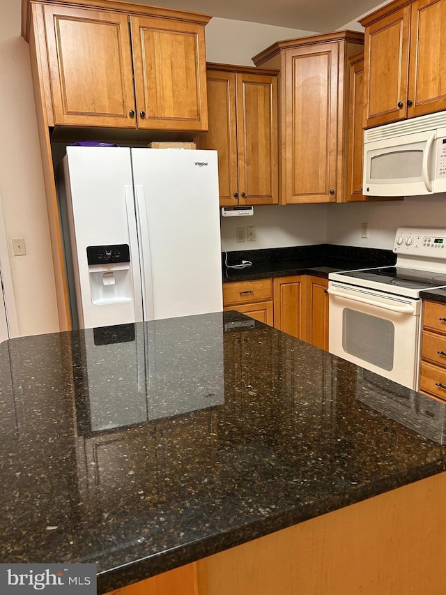 kitchen featuring white appliances and dark stone countertops