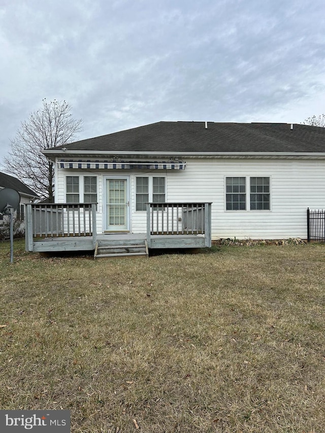 rear view of house with a wooden deck and a lawn