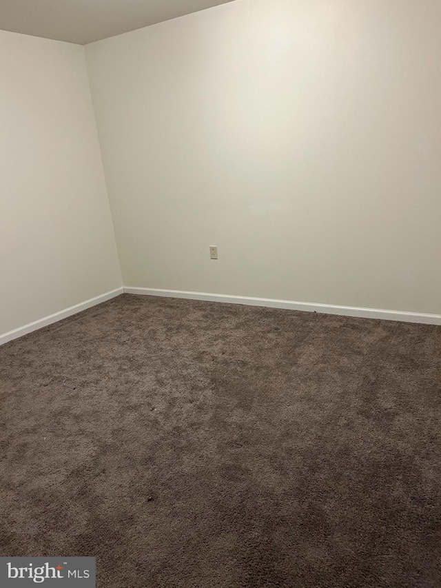 spare room with dark colored carpet