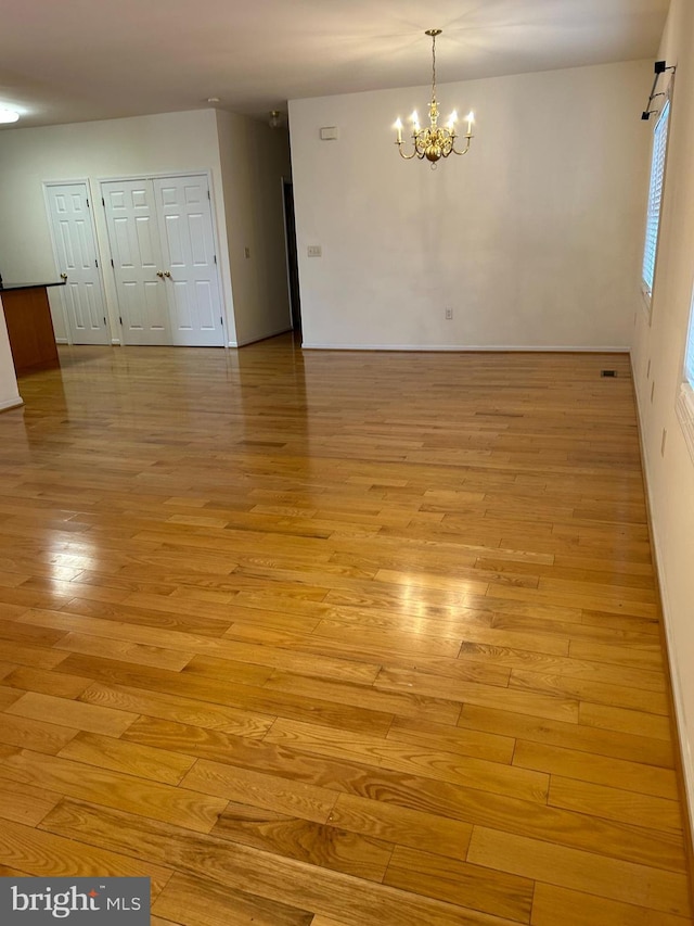 empty room with an inviting chandelier and light wood-type flooring