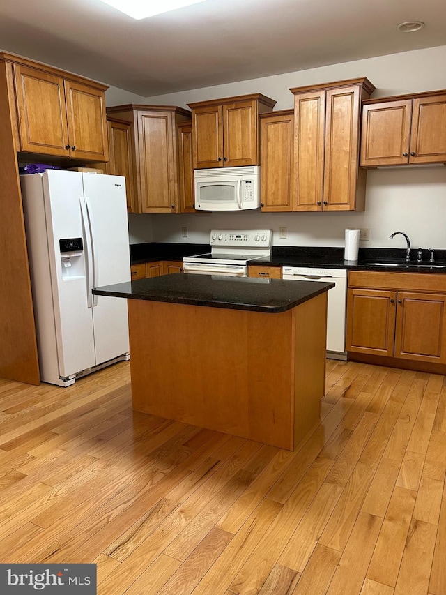 kitchen featuring sink, white appliances, a center island, light hardwood / wood-style floors, and dark stone counters