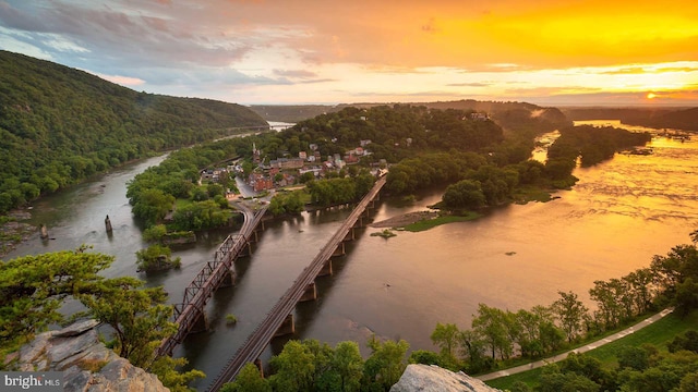 aerial view at dusk featuring a water and mountain view