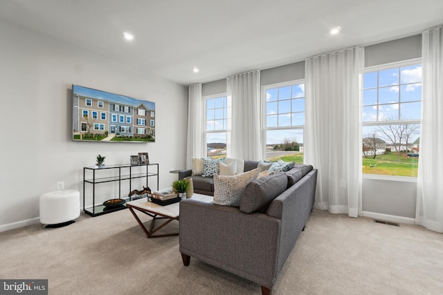 living area featuring light carpet, a wealth of natural light, visible vents, and baseboards