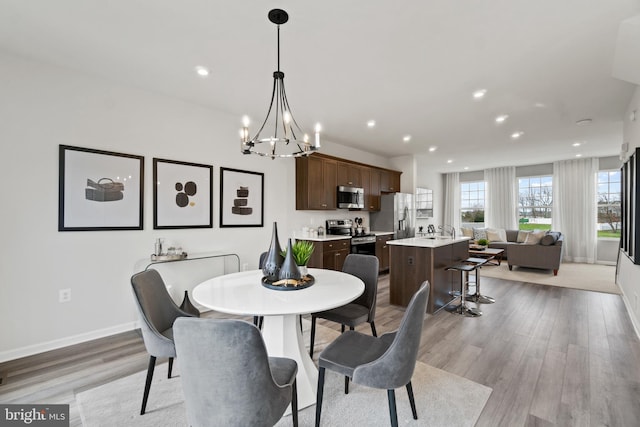 dining room featuring light wood-type flooring, baseboards, a chandelier, and recessed lighting