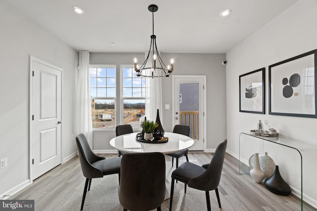 dining space with a notable chandelier, light wood finished floors, and baseboards