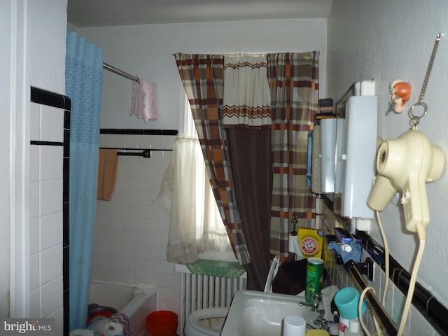 full bathroom with sink, tile walls, shower / bath combo with shower curtain, and toilet