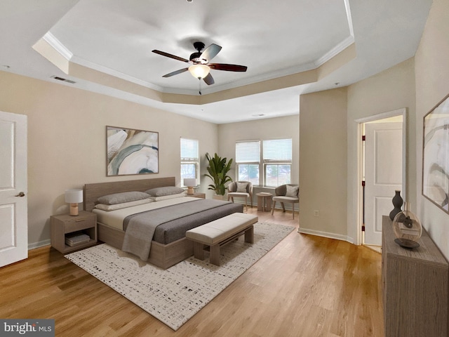 bedroom featuring a tray ceiling, ornamental molding, light hardwood / wood-style floors, and ceiling fan