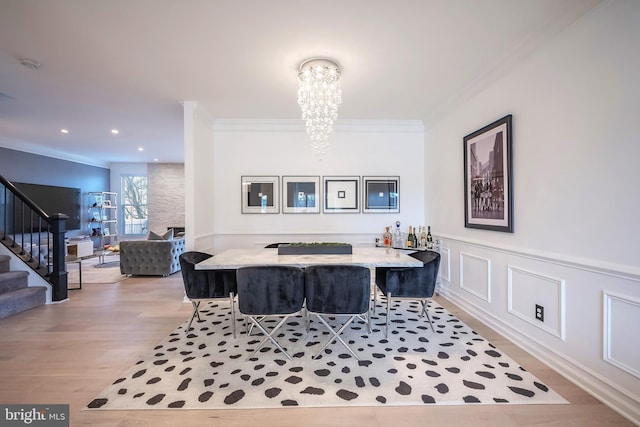 dining room with ornamental molding, an inviting chandelier, and light hardwood / wood-style flooring