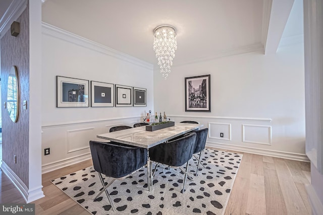 dining space featuring an inviting chandelier, ornamental molding, and light hardwood / wood-style flooring