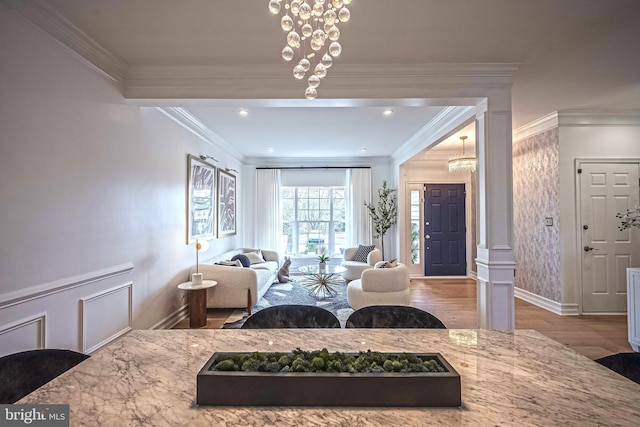 living room with ornamental molding, a chandelier, and light hardwood / wood-style flooring