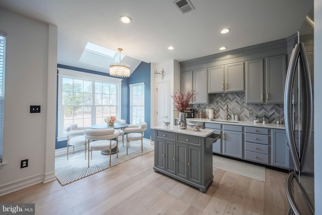 kitchen with gray cabinets, sink, stainless steel refrigerator, and decorative light fixtures