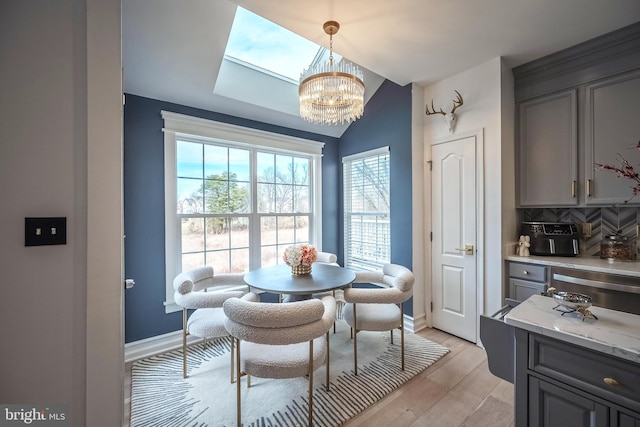 dining room with lofted ceiling, light wood-type flooring, and a notable chandelier