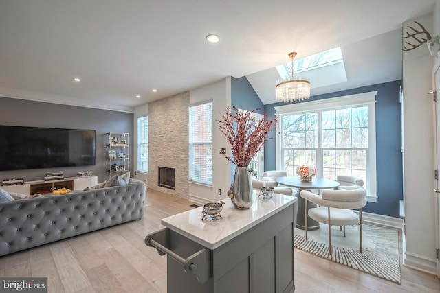 living room with a stone fireplace, a notable chandelier, and light hardwood / wood-style floors