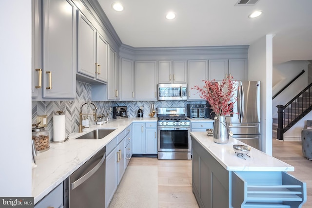 kitchen featuring light stone counters, appliances with stainless steel finishes, gray cabinets, and sink