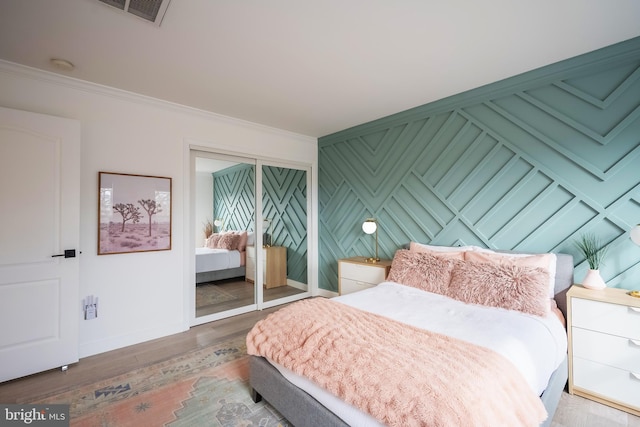 bedroom with crown molding, hardwood / wood-style floors, and a closet